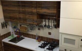 Кухня с деревянными секциями и барной стойкой, переходящей в полку