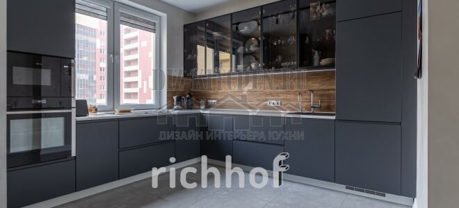 Современная кухня со стеклянными фасадами и варочной панелью под окном