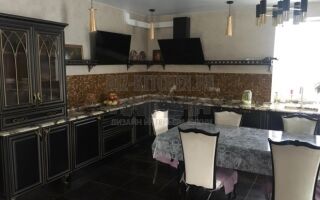 Черная классическая кухня с золотой отделкой, совмещенная с гостиной